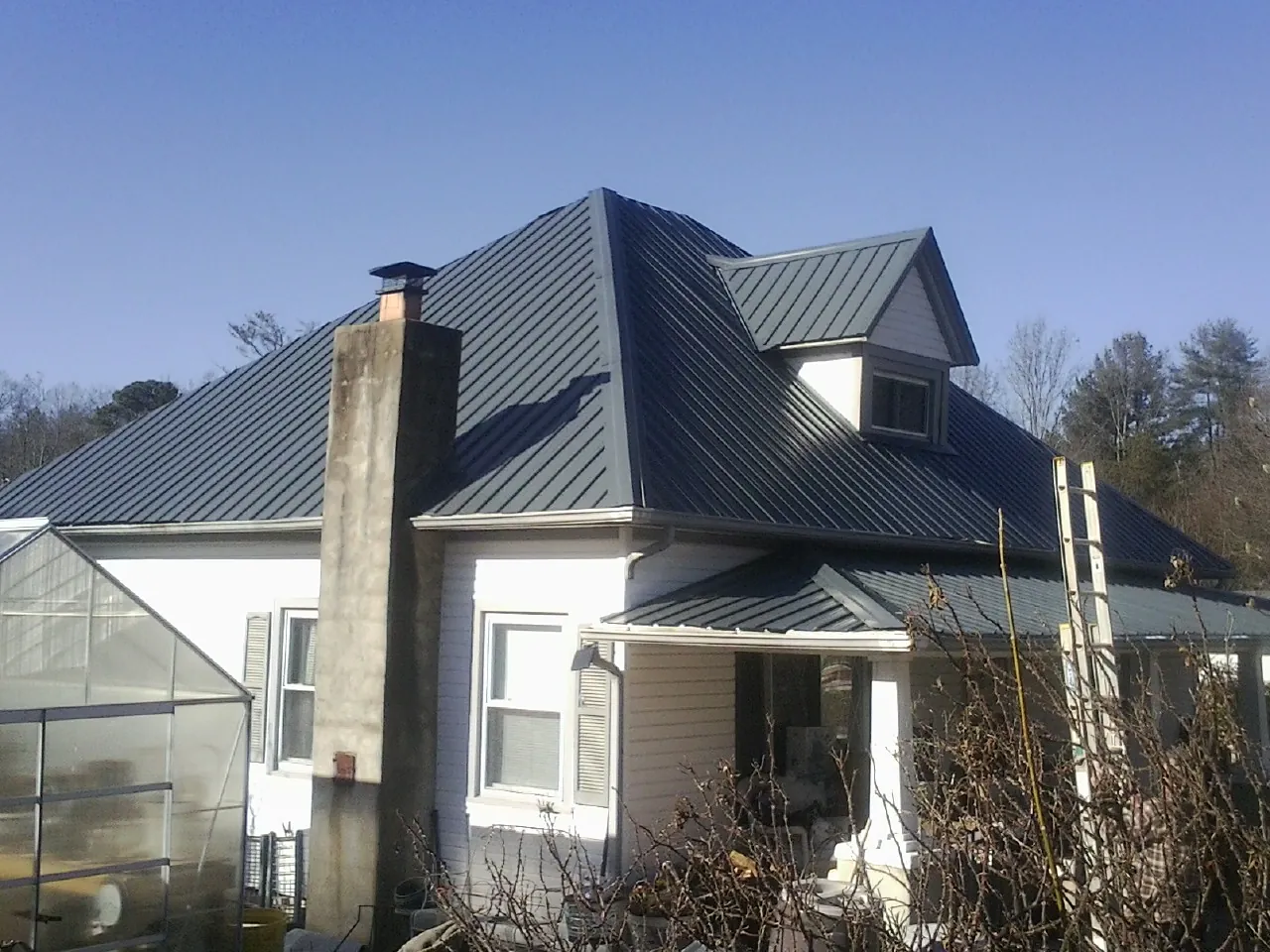 Dark blue standing seam metal roof on a white farmhouse with dormer — Slate & Tile Roof Repair by Roofing Brothers in Miamisburg