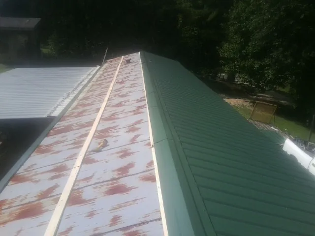 Old rusted panels beside newly installed green metal roofing — Wind Damage Roof Repair by Roofing Brothers in Miamisburg