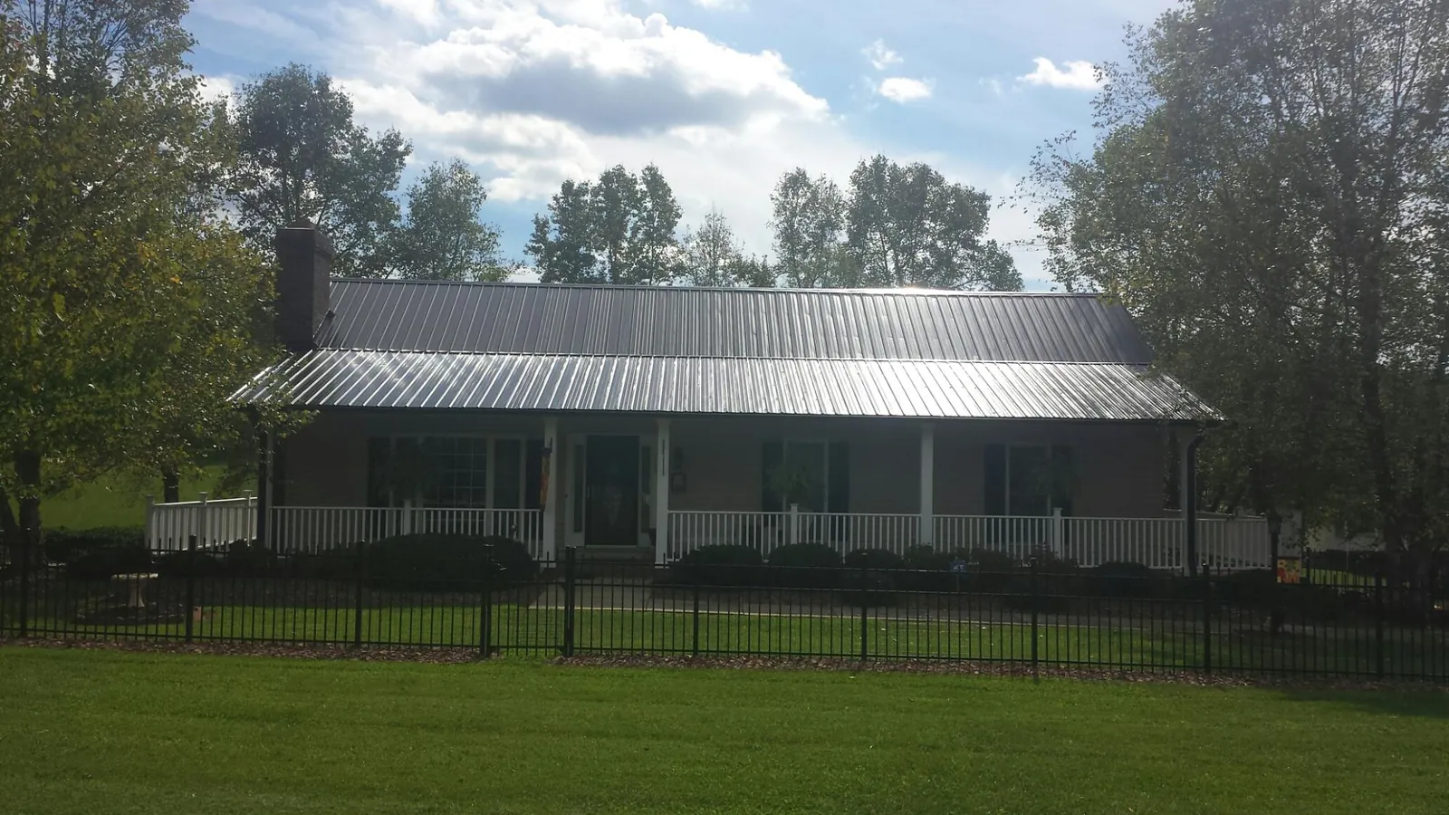 Gray metal roof on a brick ranch with a full width front porch — Gutter Guard Installation work by our crew in Miamisburg