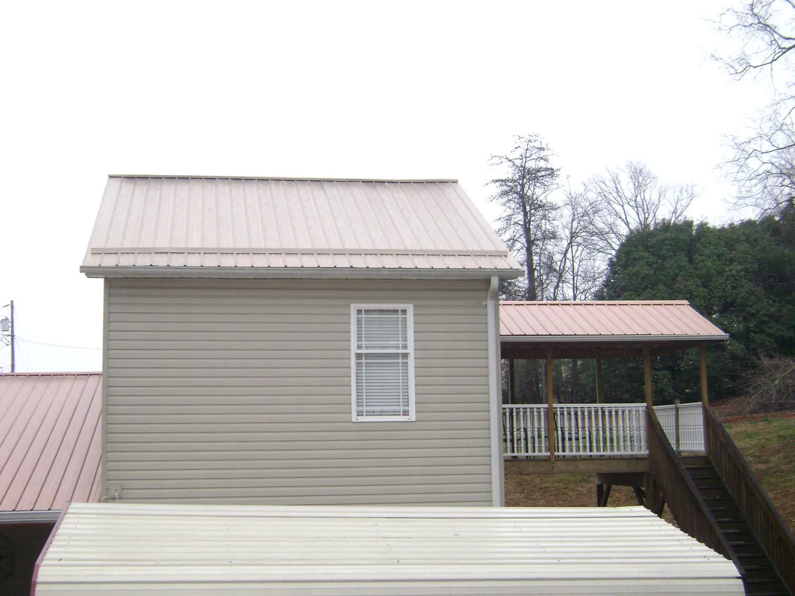 Tan metal roofs on a two story addition and attached porch, from a Roof Replacement job in Miamisburg