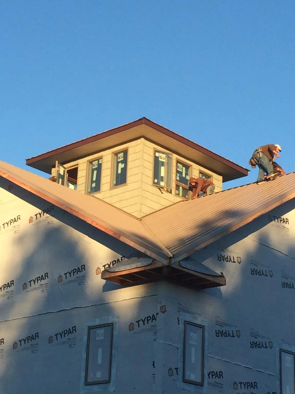 Roofers working around a rooftop cupola on a new metal roof at sunset — Roof Waterproofing in Miamisburg by Roofing Brothers